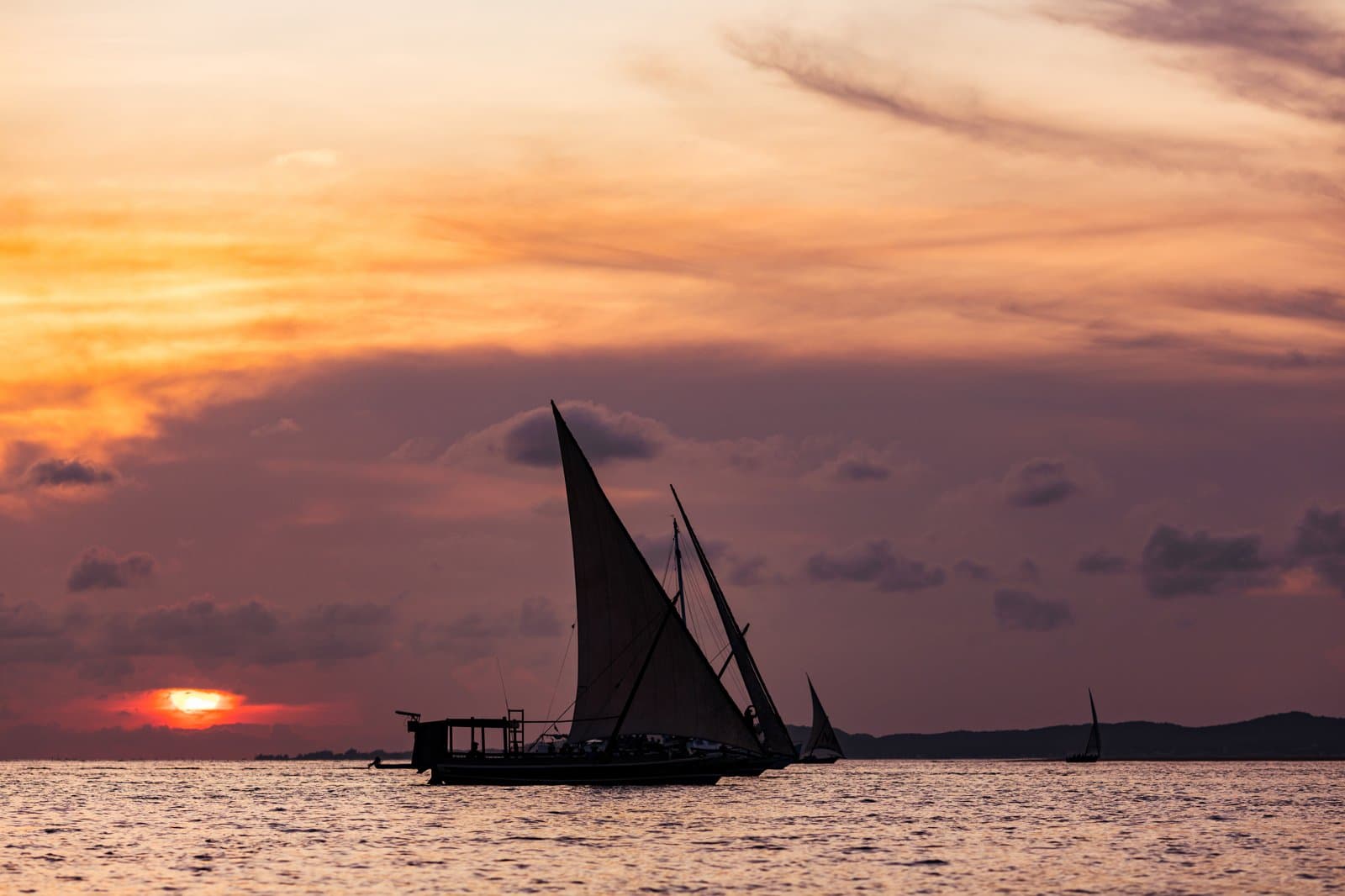 Traditionelle Dhow-Segelboote silhouettiert vor dem Sonnenuntergang an Kenias Küste
