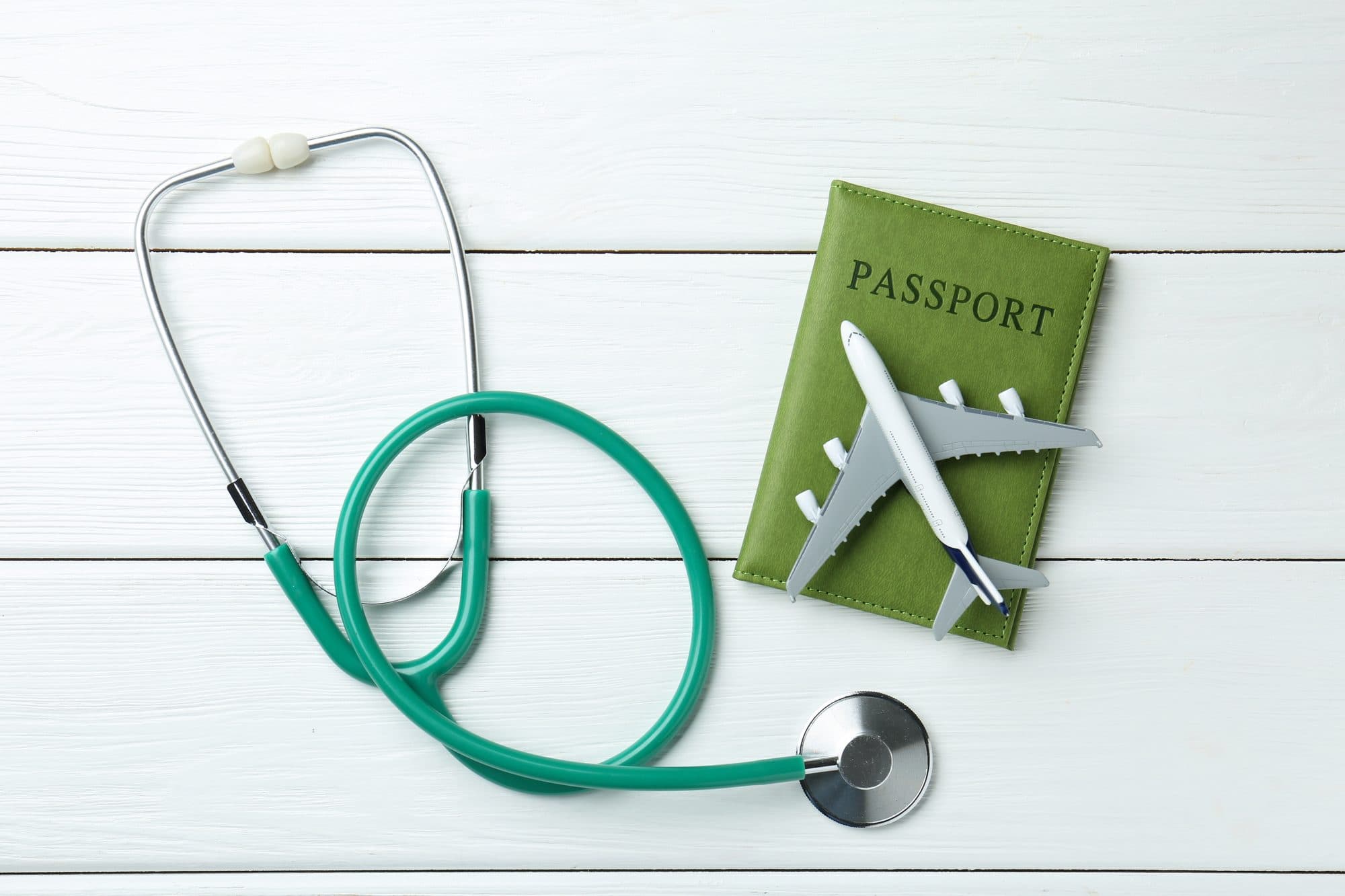 Reisepass, Stethoskop und Flugzeugmodell als Sinnbild für reisemedizinische Vorbereitung