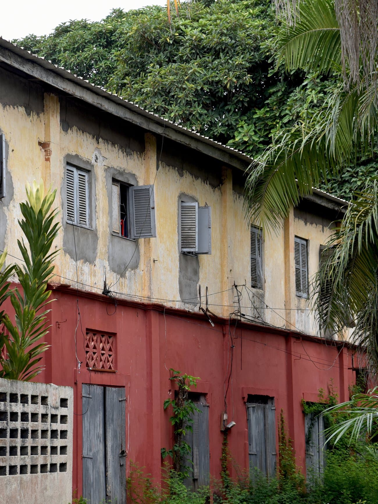 Verwittertes Kolonialhaus mit rot-gelber Fassade im UNESCO-Welterbe Grand-Bassam, Elfenbeinküste