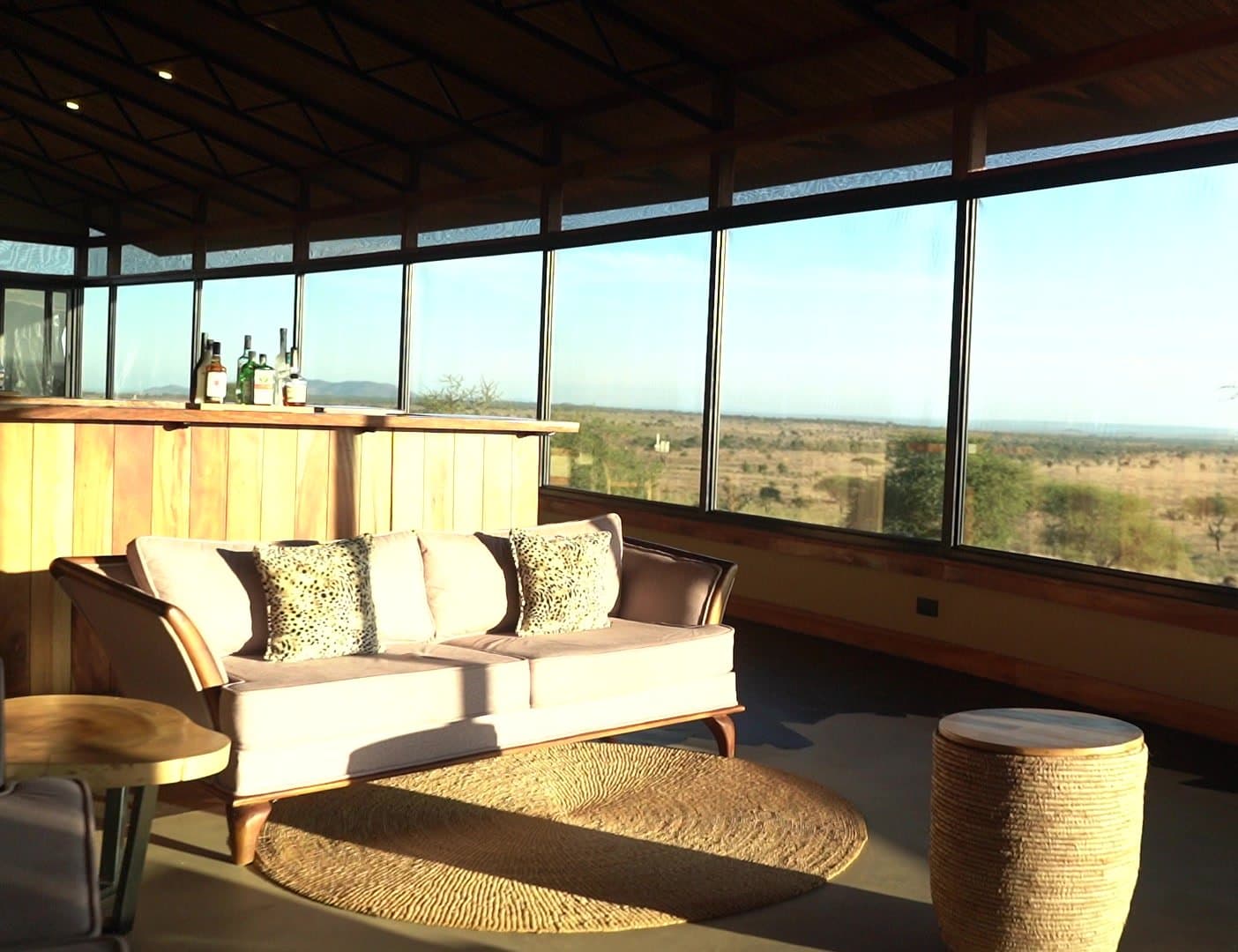 Lounge einer Luxus-Lodge mit Panoramafenster und Blick auf die Savanne