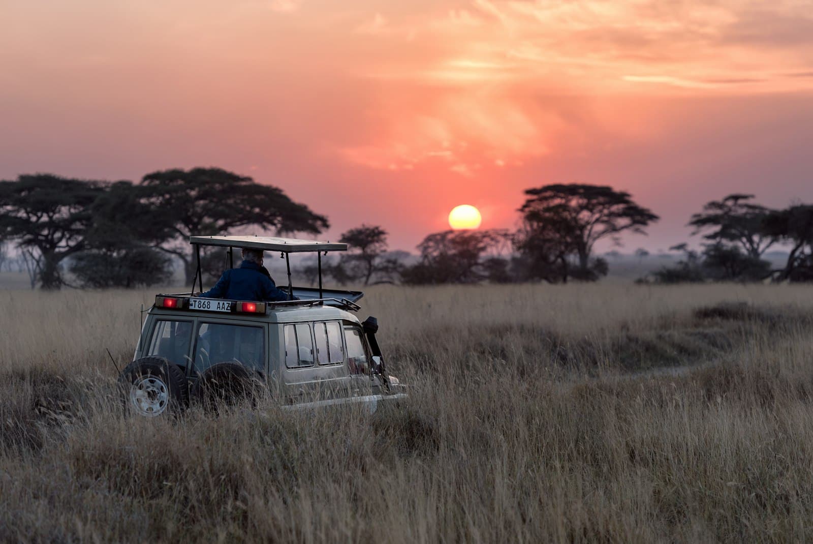 Safari-Jeep bei Sonnenuntergang in der Serengeti — starten Sie Ihre Tansania-Reiseplanung