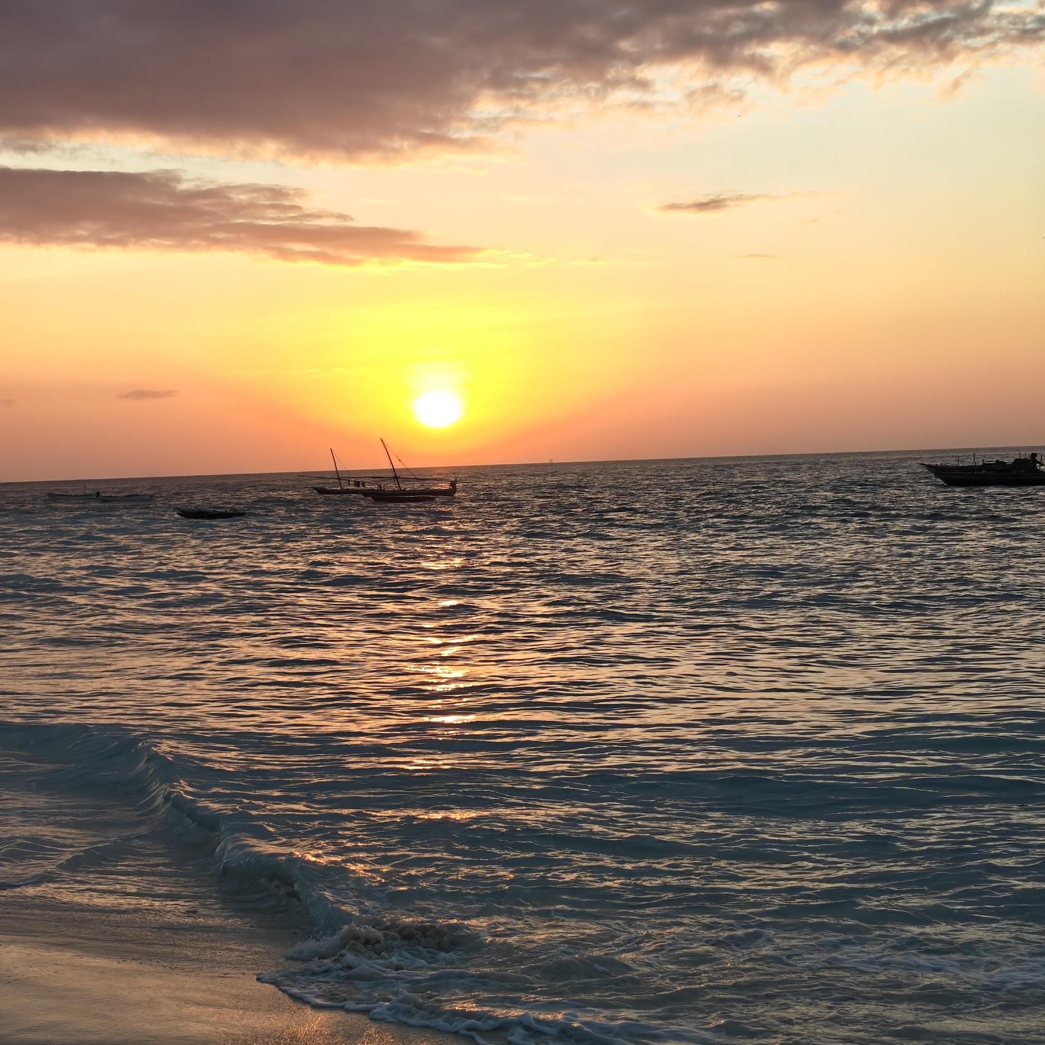 Fischerboote treiben bei Sonnenuntergang im Indischen Ozean vor Sansibar