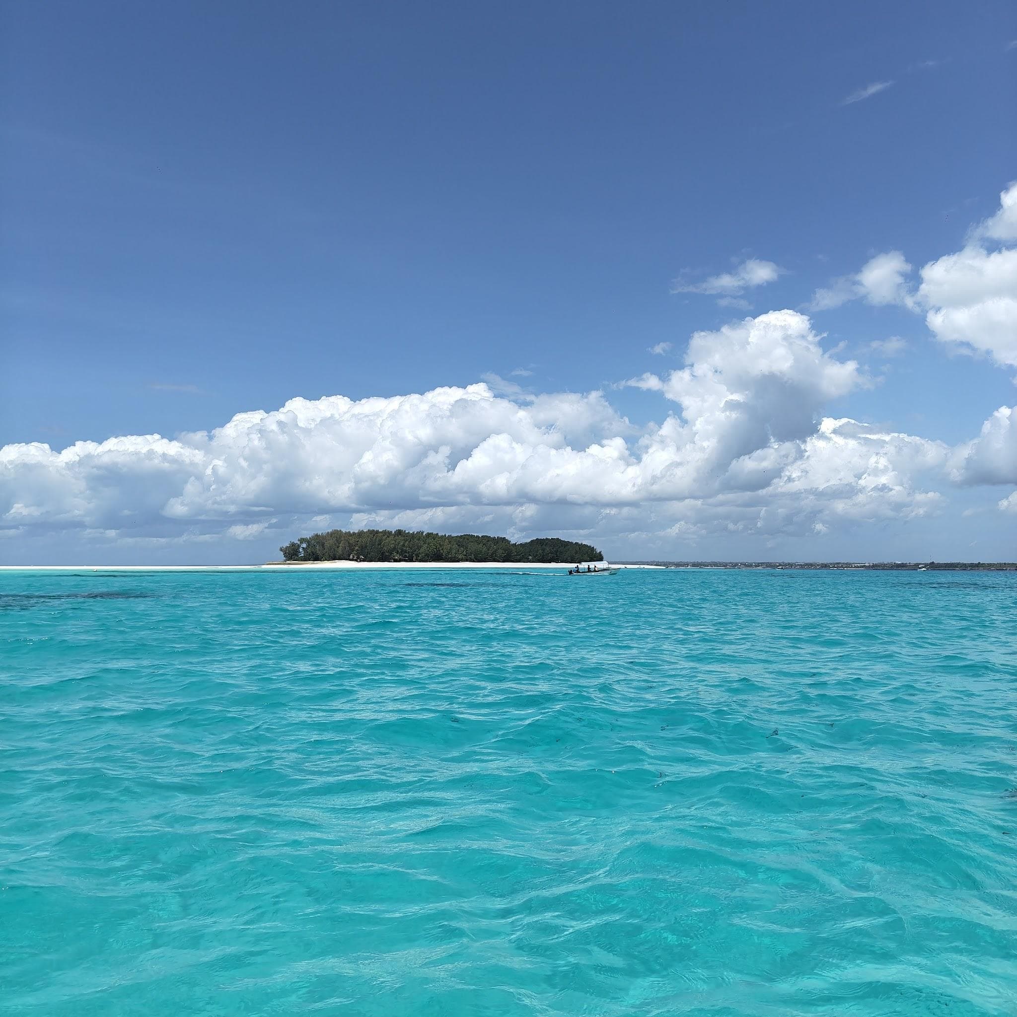 Türkisfarbenes Wasser mit Blick auf die bewaldete Mnemba Island vor Sansibar