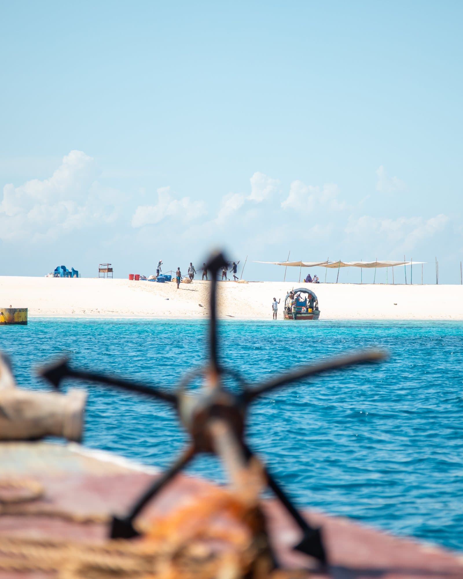 Blick vom Bug einer Dhow auf eine Sandbank vor Sansibar mit Ausflugsbooten und Besuchern