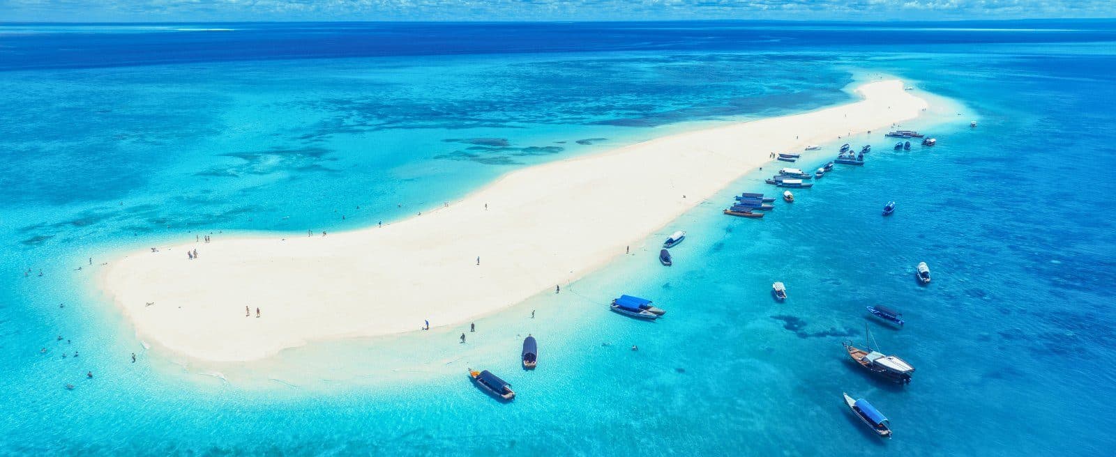 Touristen und Ausflugsboote auf einer Sandbank vor Sansibar