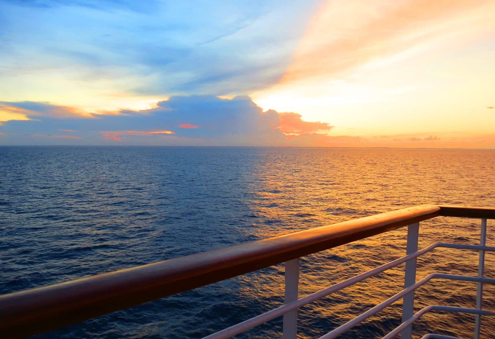 Blick vom Sonnendeck eines Kreuzfahrtschiffs bei Sonnenuntergang auf das offene Meer