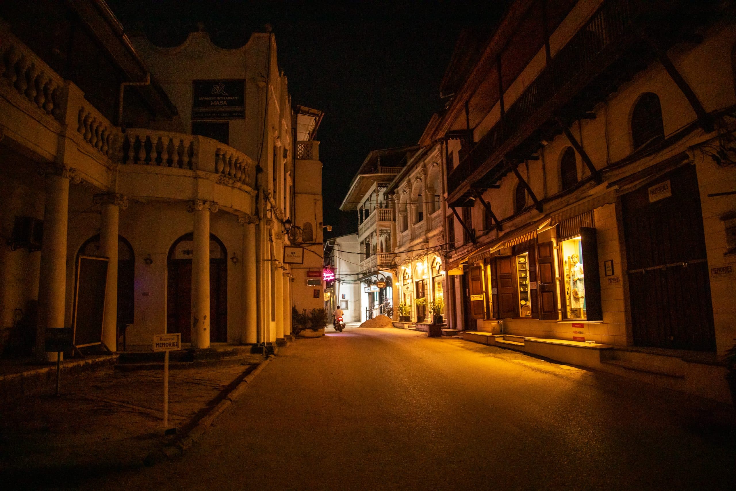 Beleuchtete Straße in der Altstadt von Stone Town am Abend mit historischen Häusern und Holzbalkonen