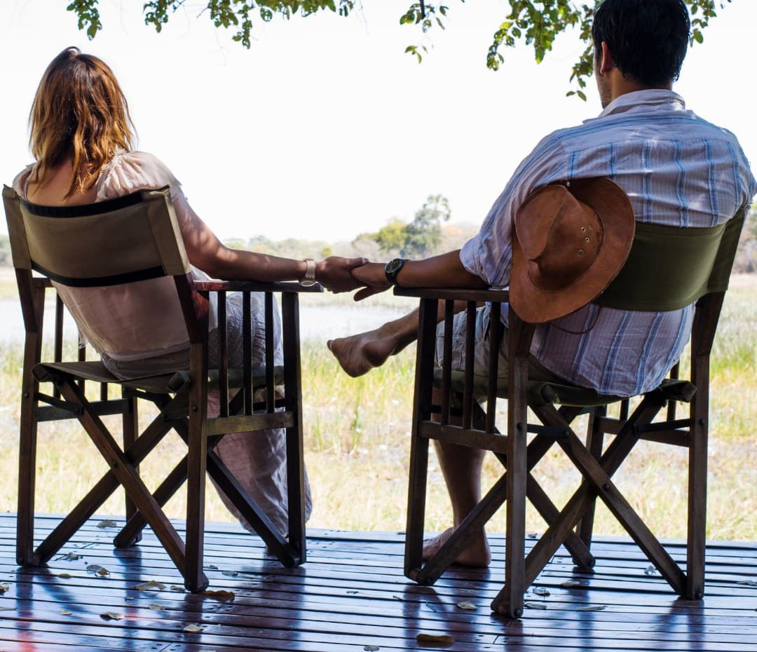 Paar auf der Terrasse einer privaten Safari-Lodge — romantische Flitterwochen in der Serengeti