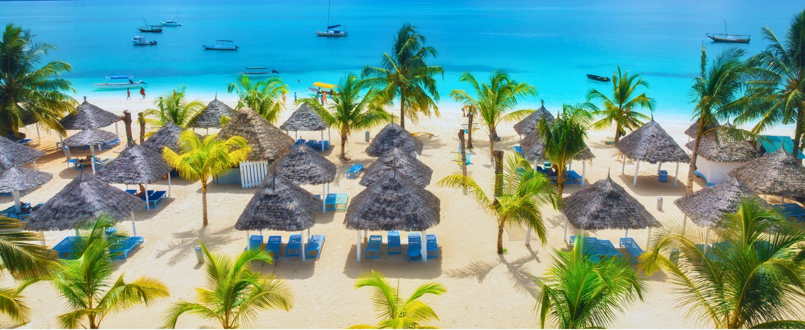 Nungwi-Strand mit traditionellen Makuti-Sonnenschirmen und Liegestühlen unter Kokospalmen