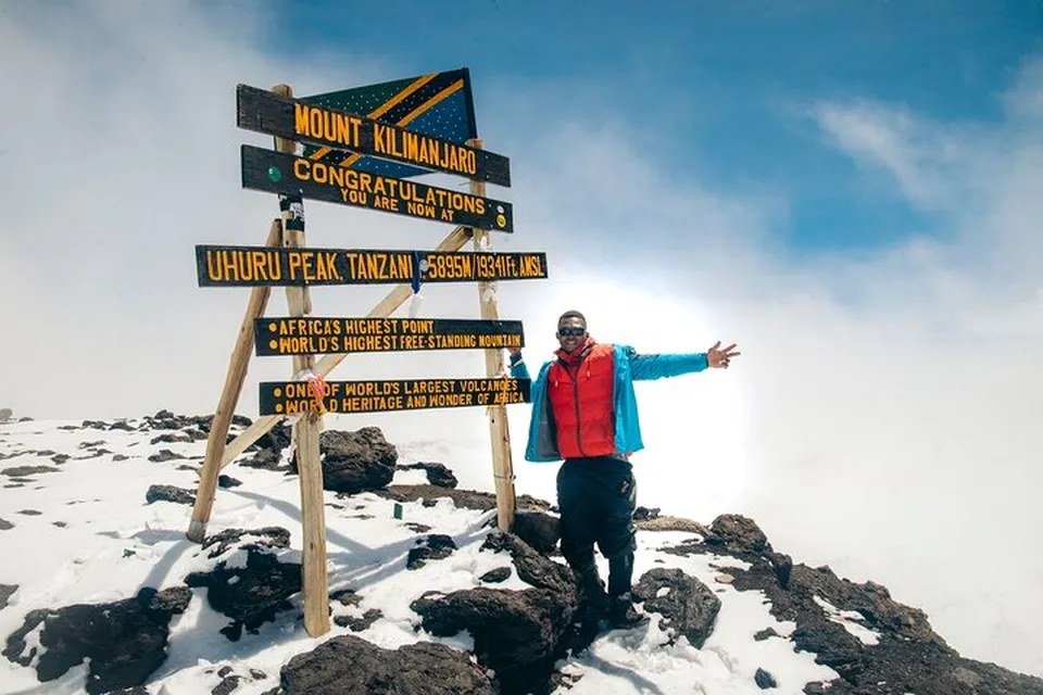 Bergsteiger am Uhuru Peak (5.895 m) auf dem Kilimandscharo nach dem Aufstieg über die Lemosho Route.